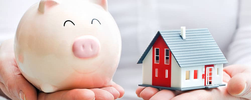 woman holding a piggy bank and house model